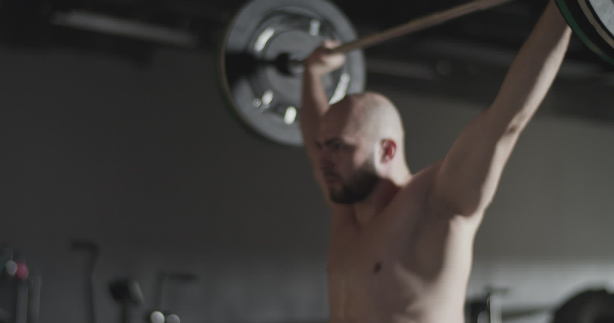Concentrated sportsman doing squats with barbell