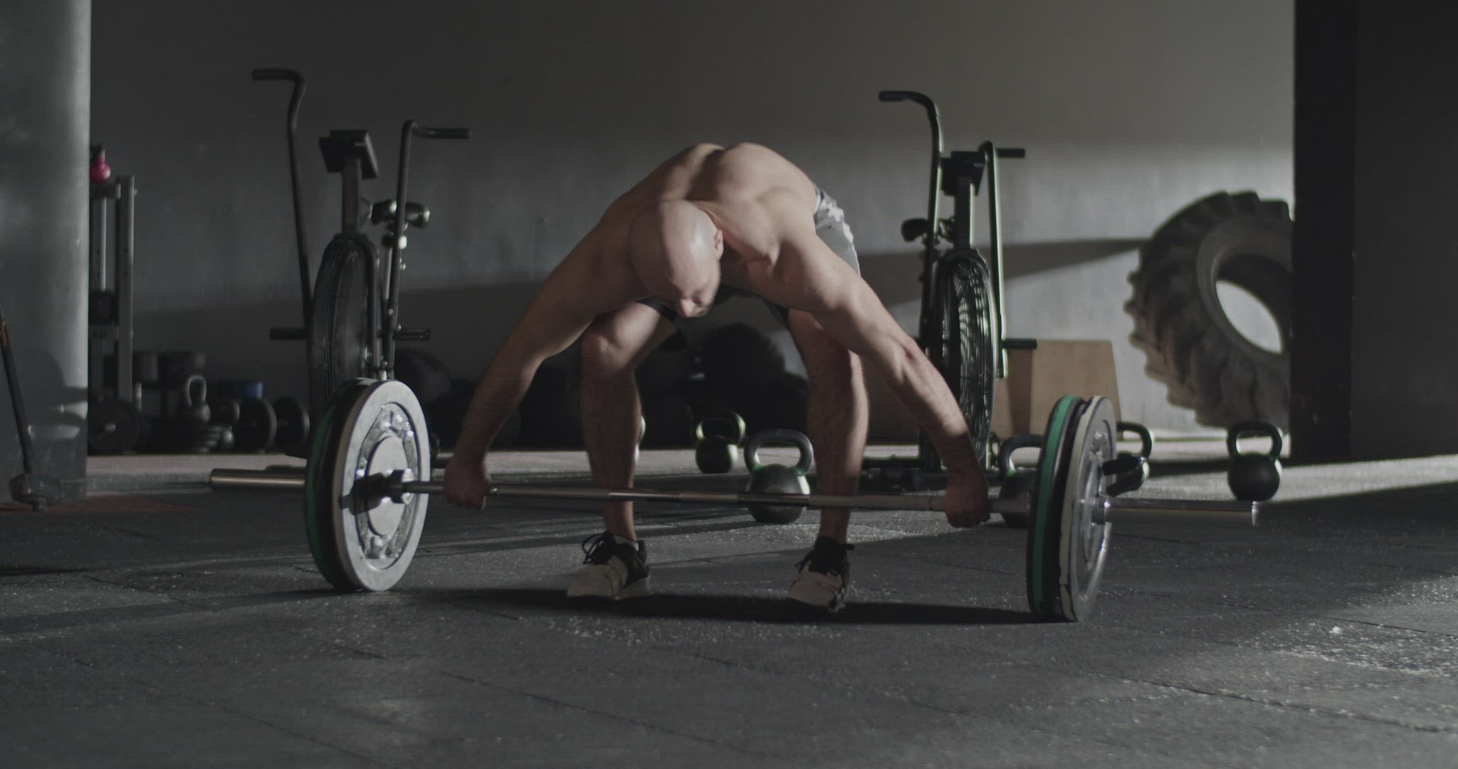 Muscular sportsman doing snatch exercise with barbell