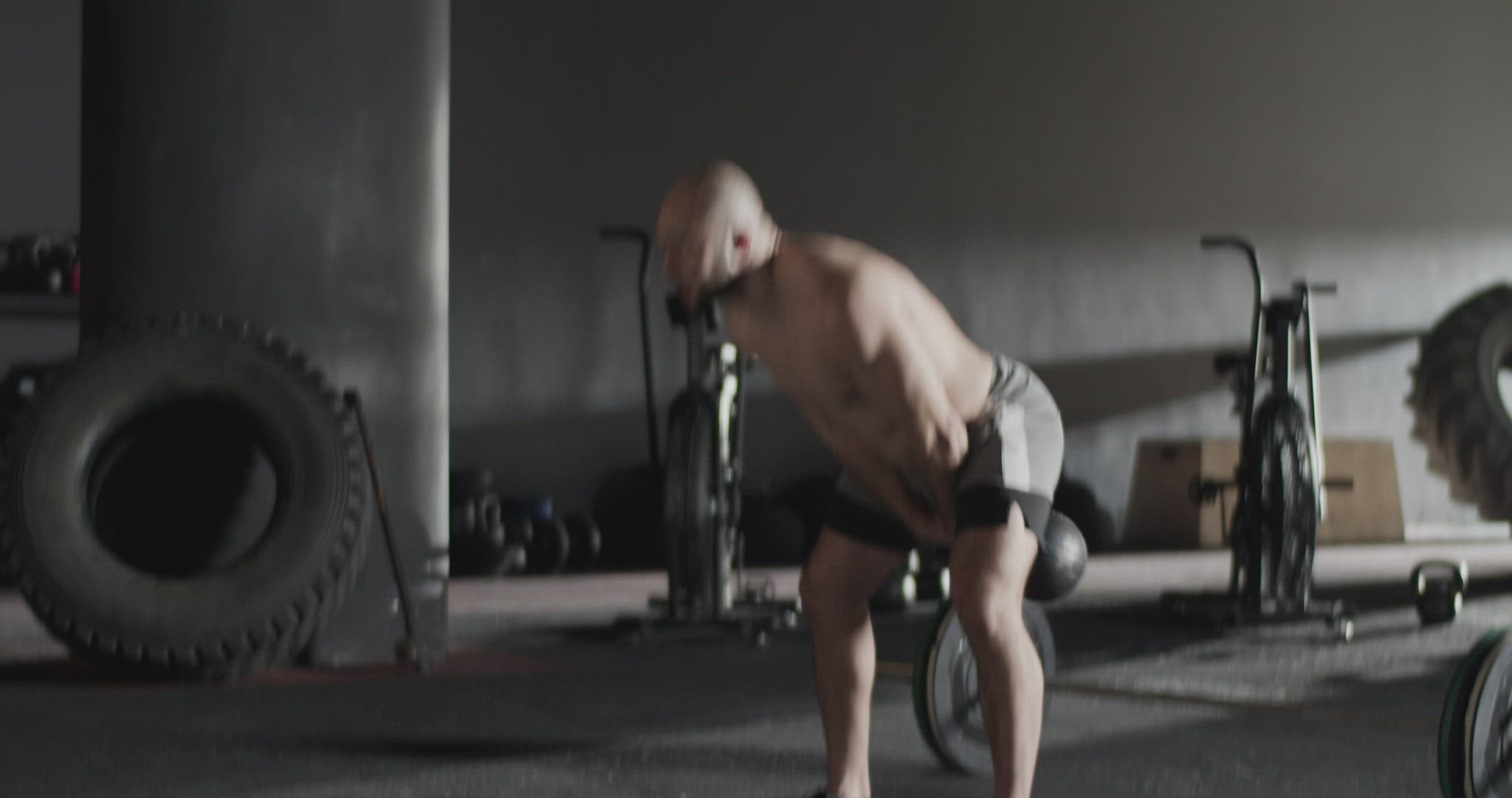 Muscular sportsman doing kettlebell swings in gym