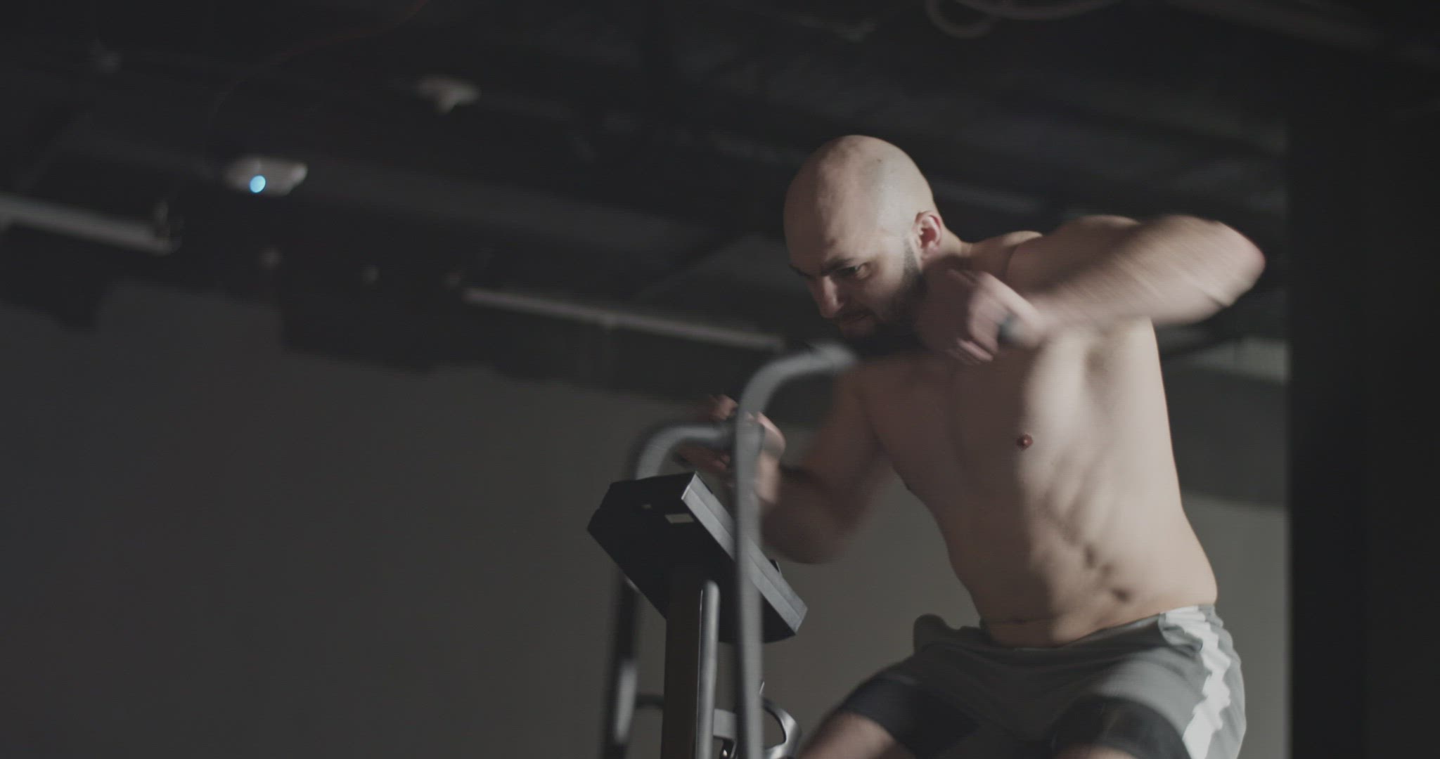 Muscular sportsman exercising on air bike