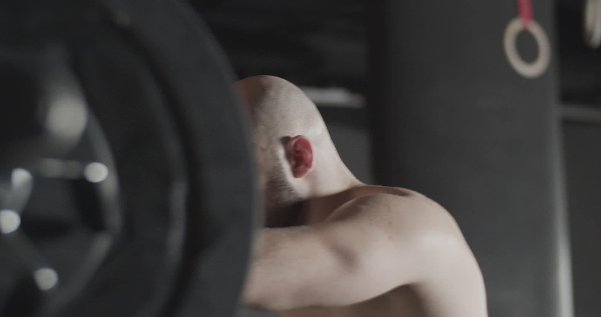 Focused sportsman doing squats with barbell during training