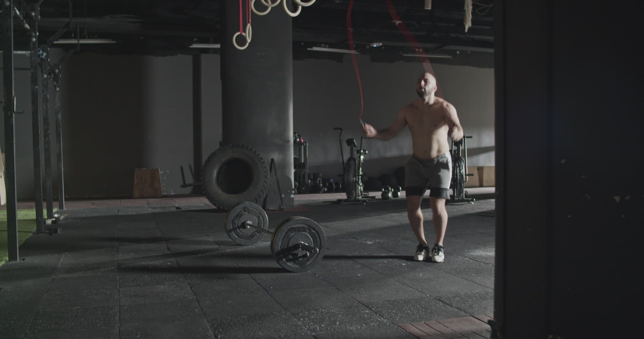 Shirtless sportsman jumping rope during training in gym