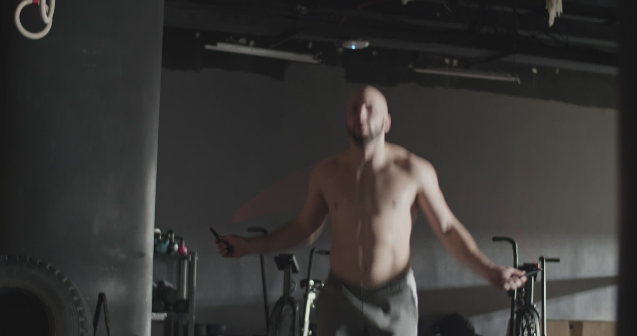Shirtless sportsman jumping rope during training in gym