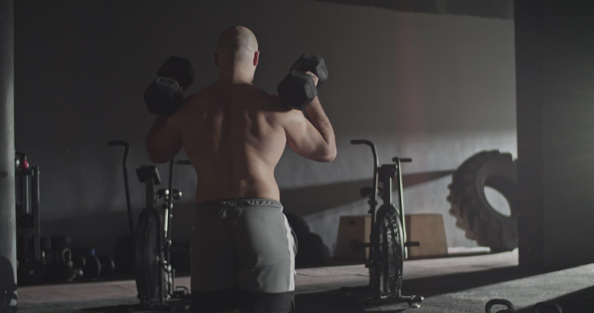 Fit shirtless sportsman doing lunges with dumbbells