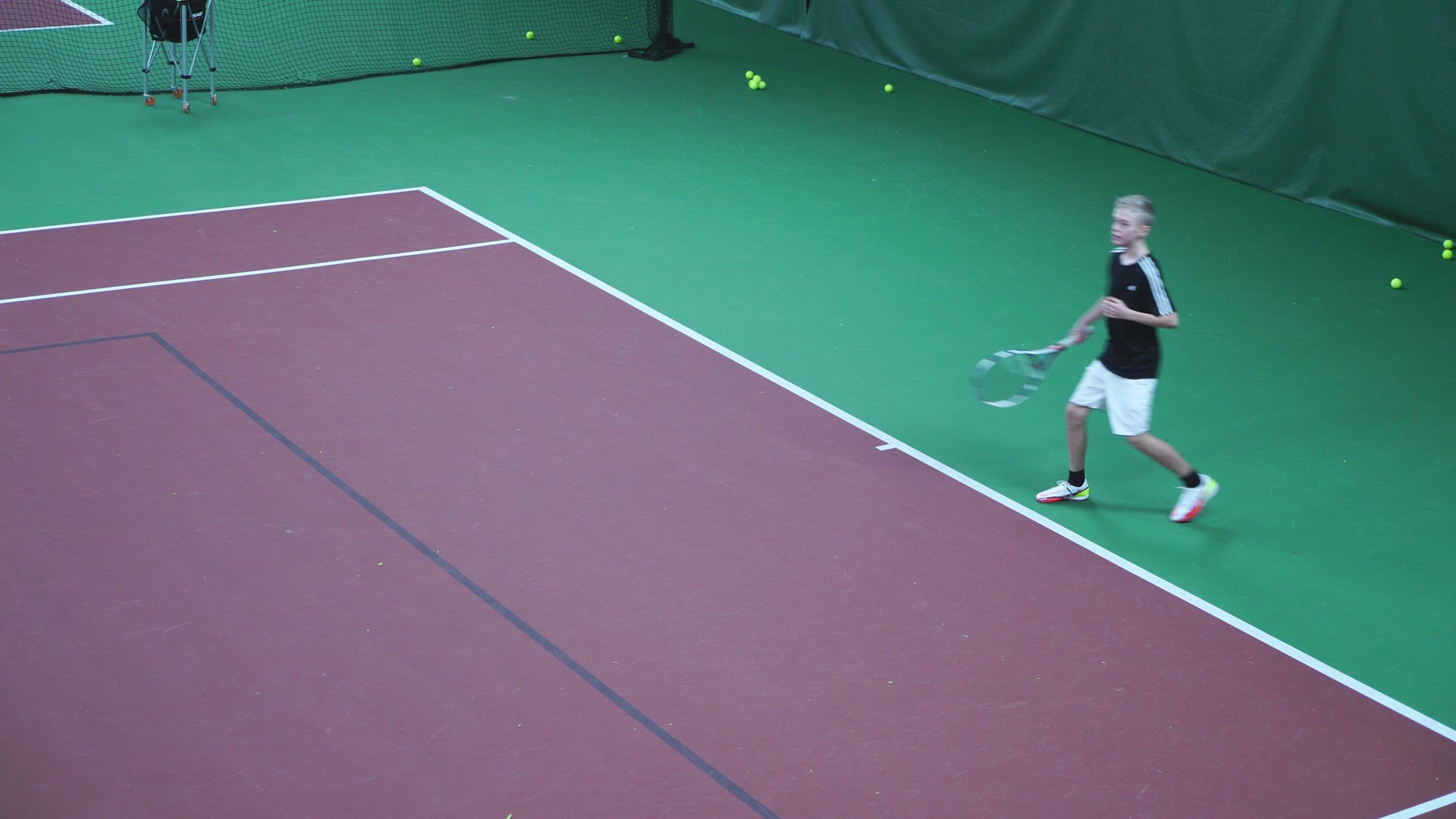boy practising tennis - indoor tennis court - 