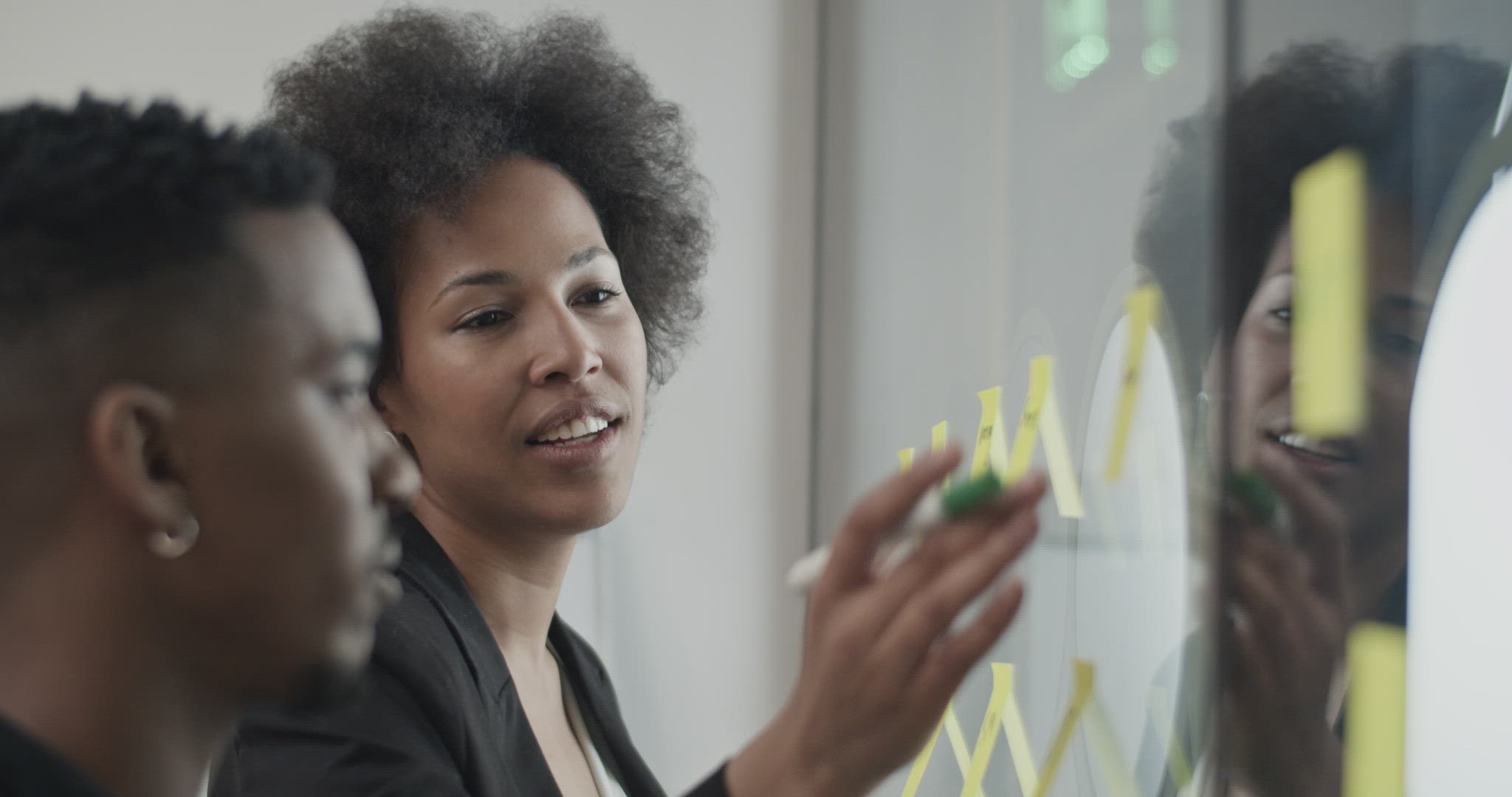 Black colleagues brainstorming near glass wall