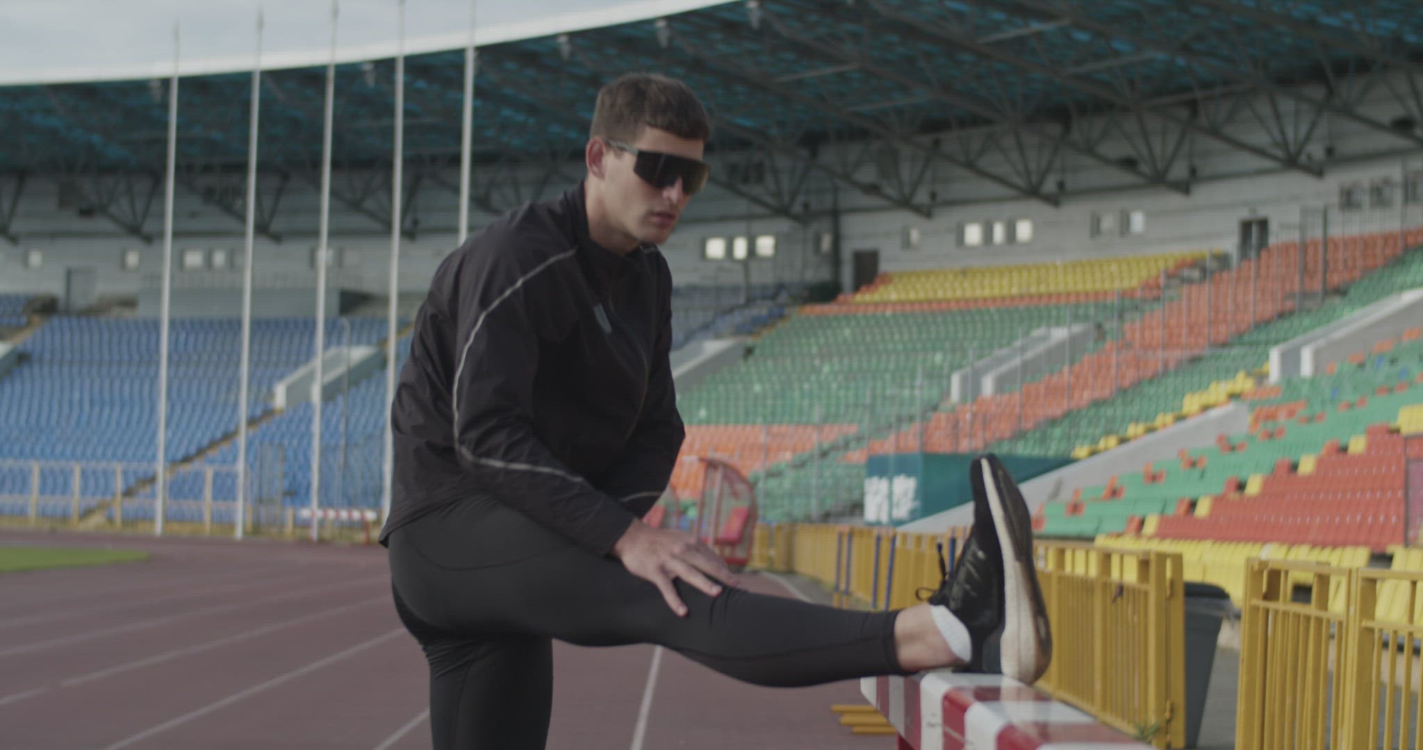 Young athlete warming up near barrier