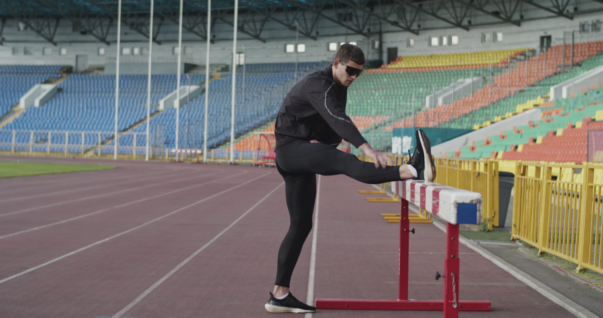 Young athlete warming up near barrier