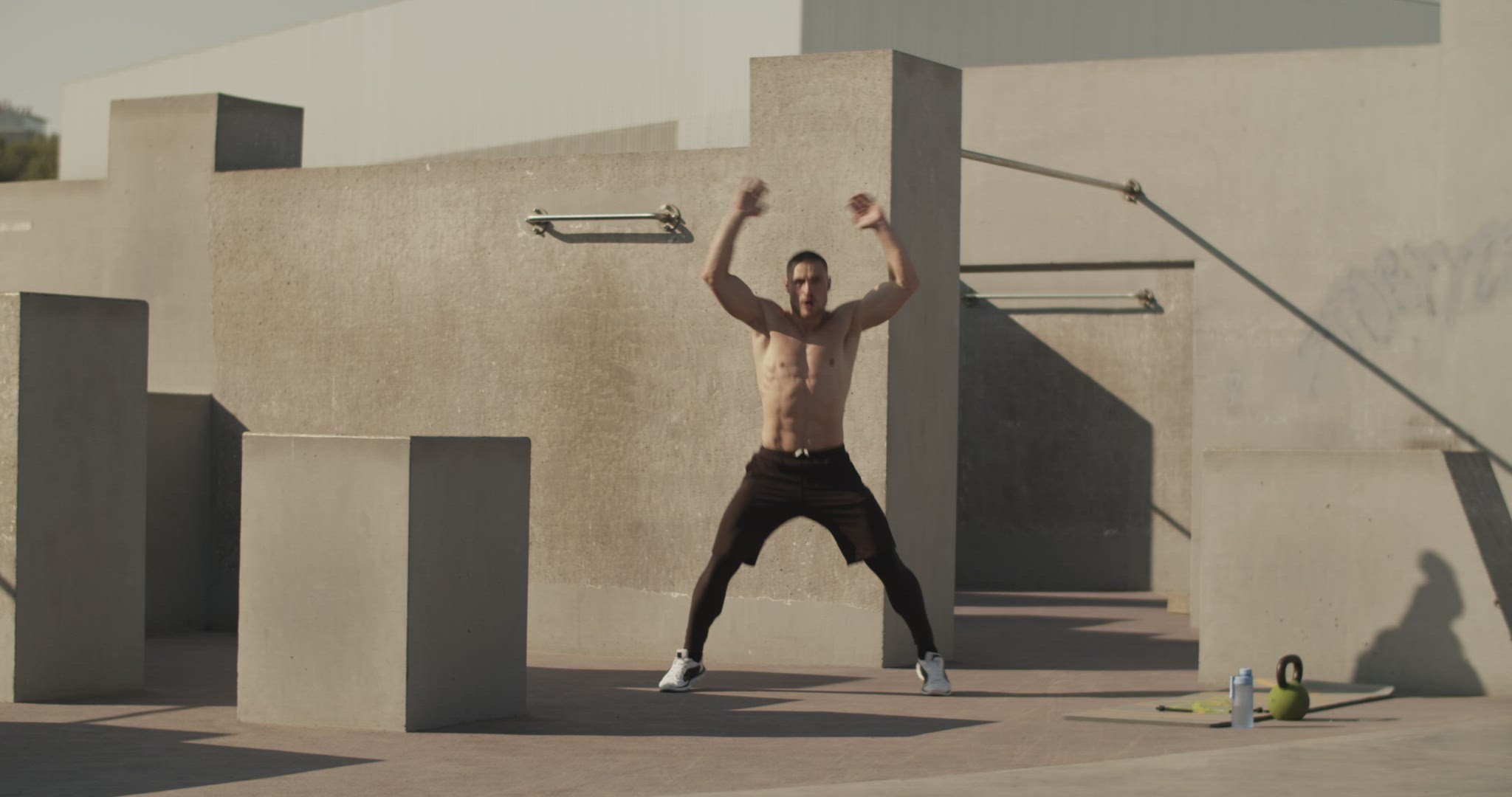Sportsman doing jumping jacks on sports ground