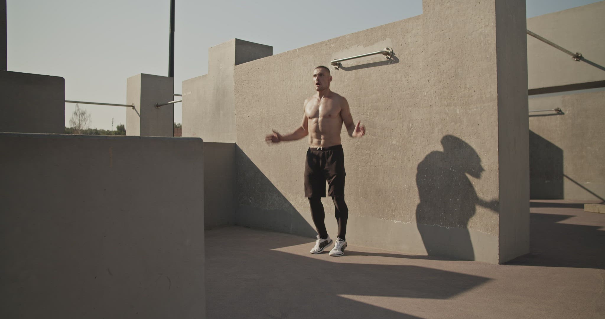 Sportsman doing jumping jacks on sports ground