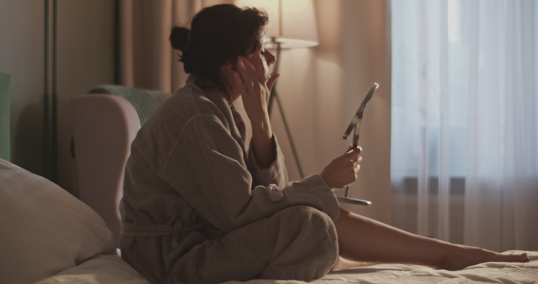 Woman doing skin care routine on bed at home
