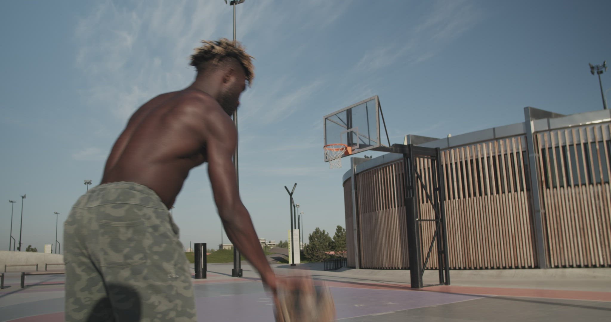 Shirtless black athlete throwing ball into ring