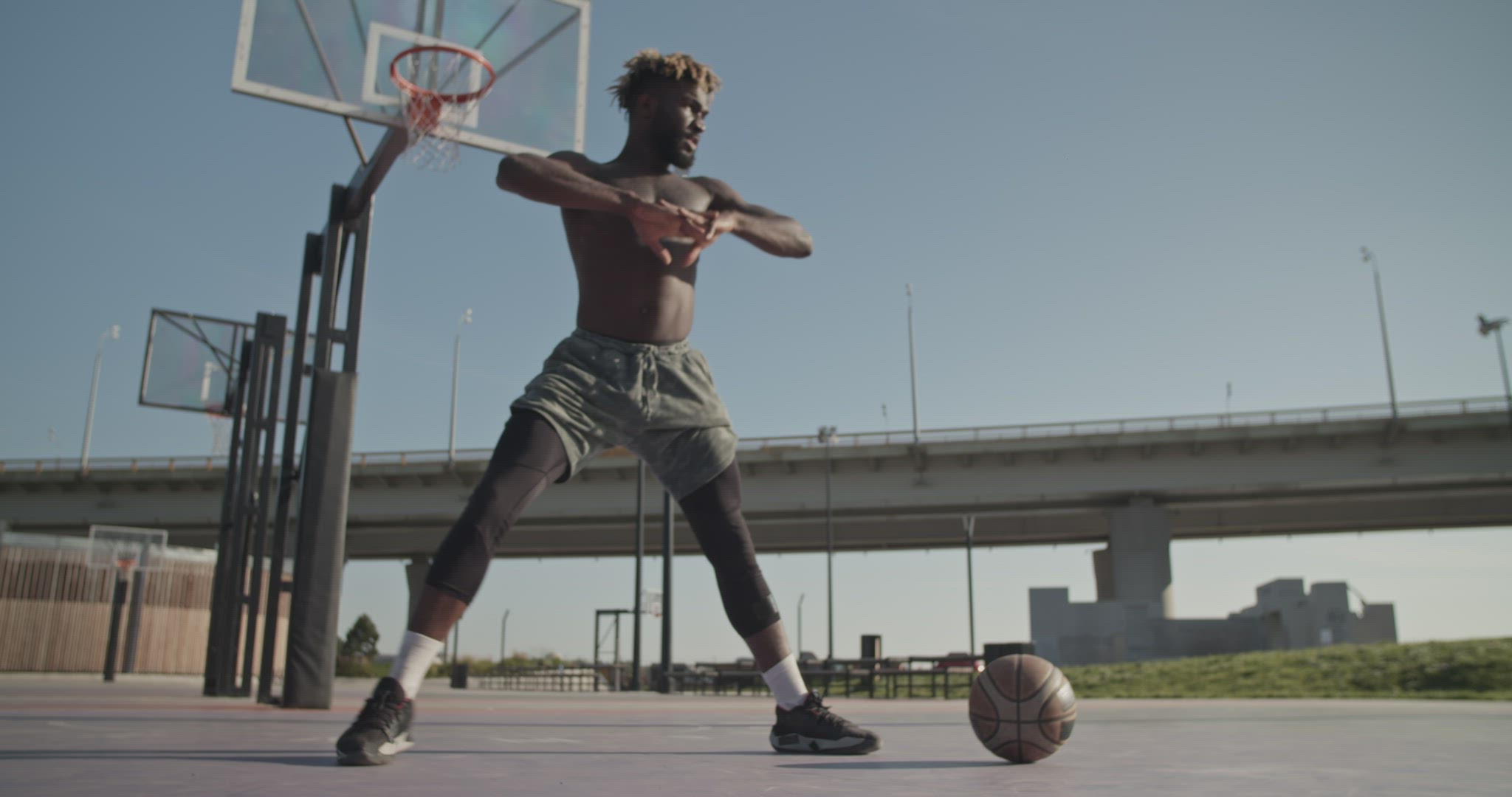 Black sportsman warming up on streetball court