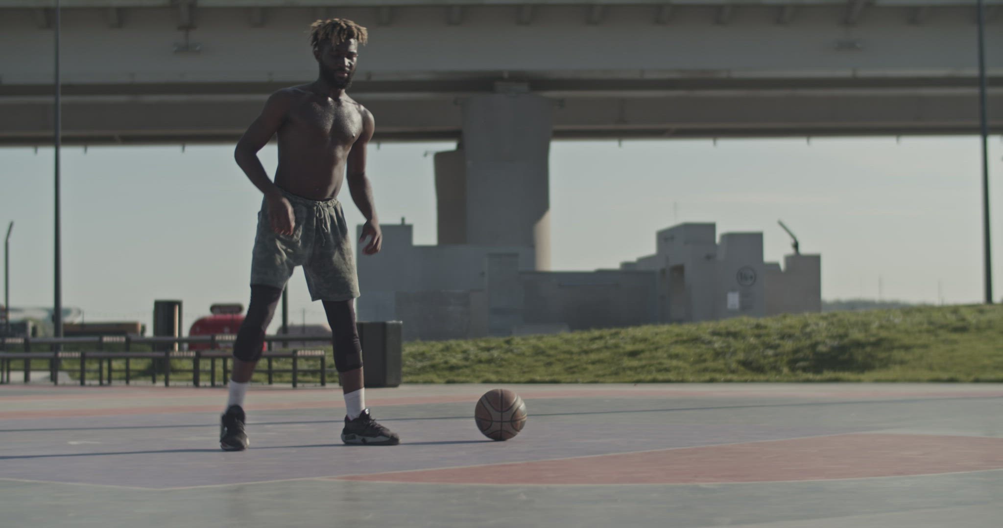 Black sportsman warming up on streetball court