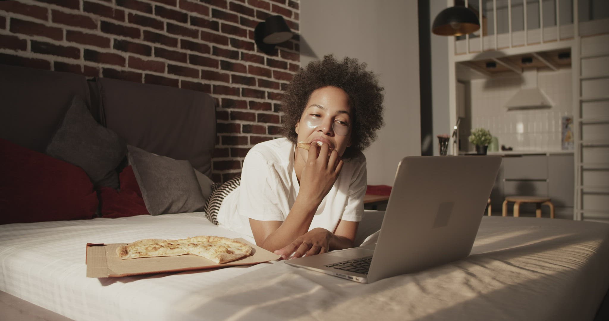 African American female eating pizza while watching film