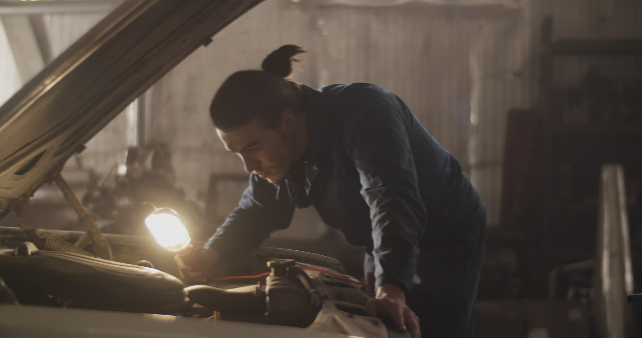 Male technician illuminating car motor