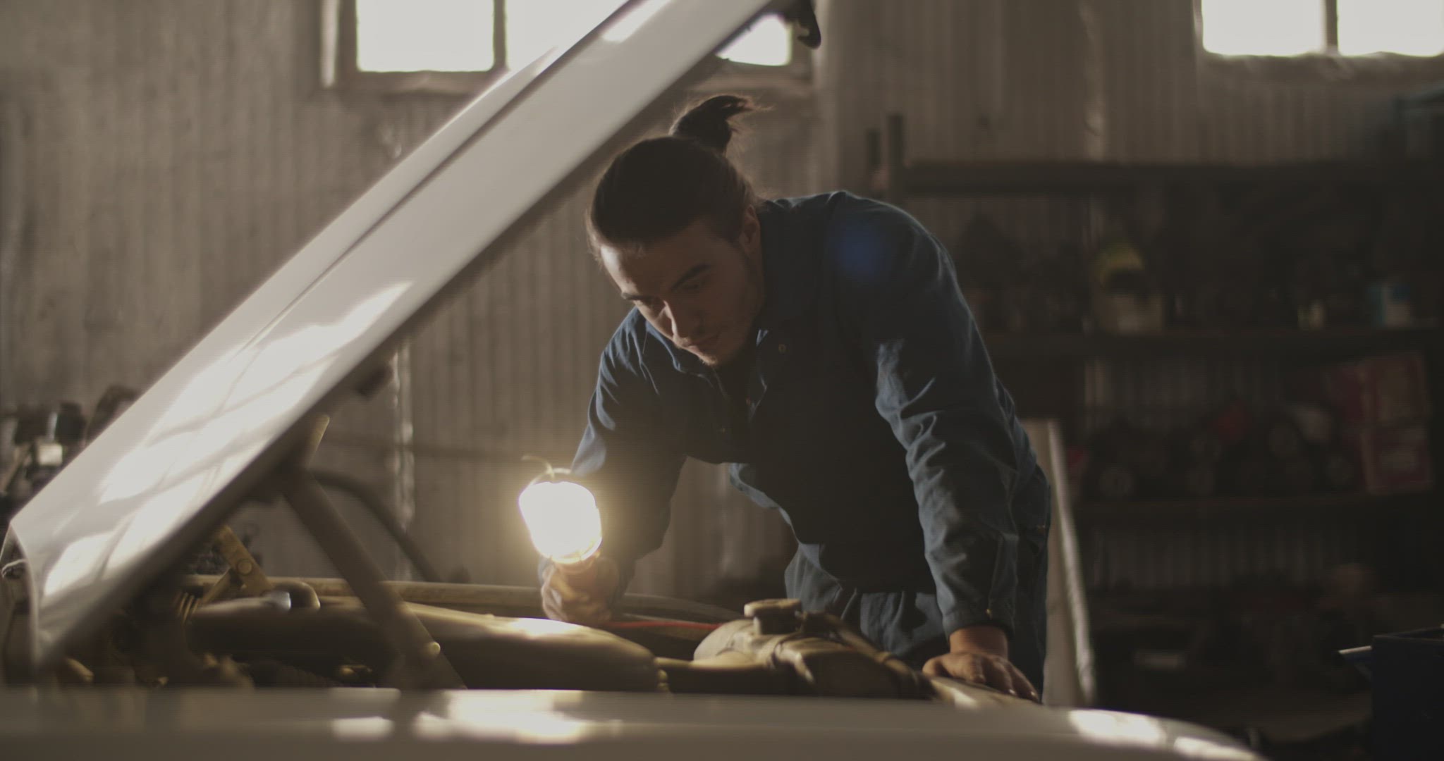 Male technician illuminating car motor