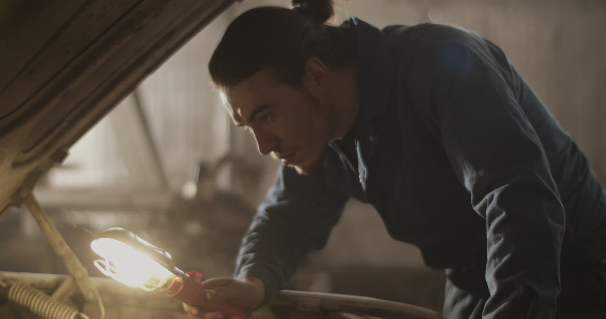 Male technician illuminating car motor