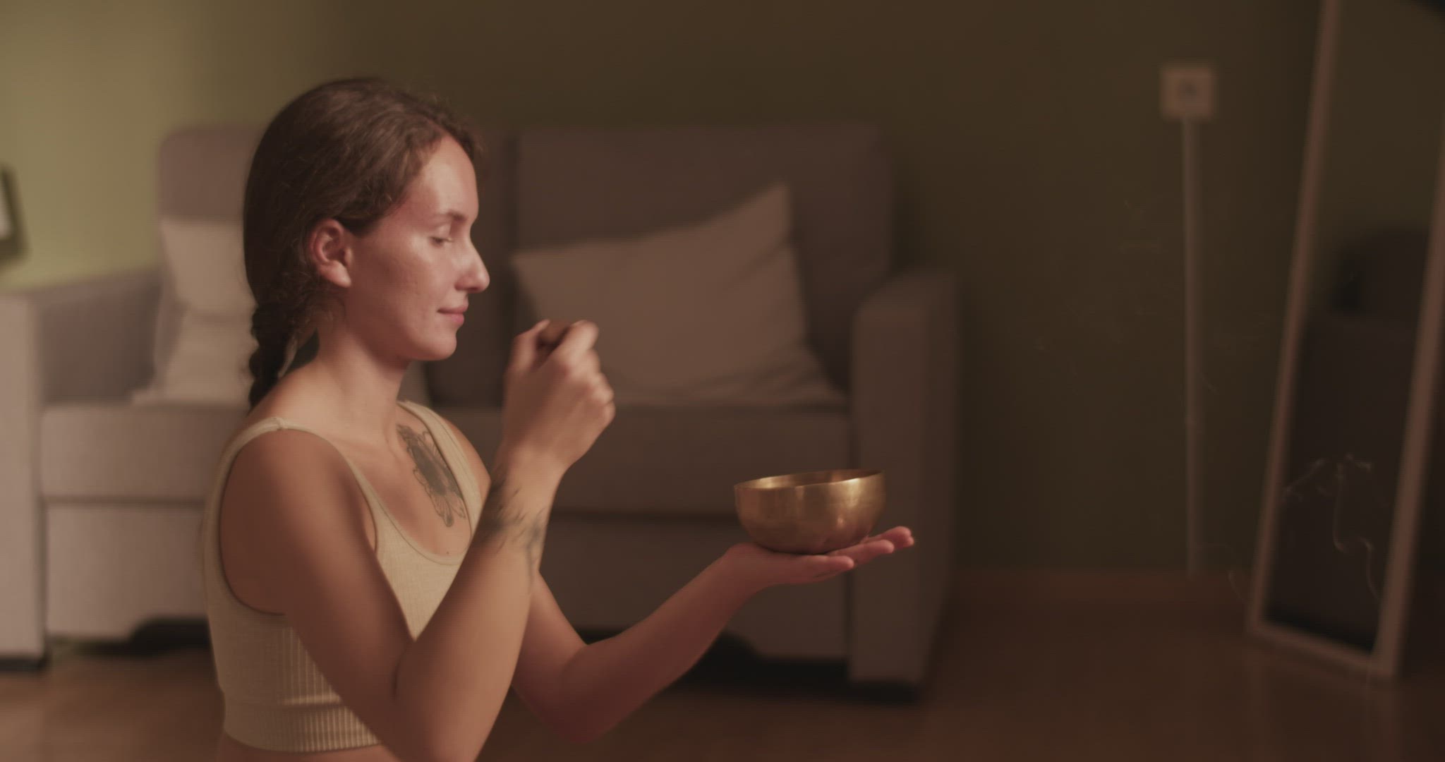 Woman meditating with singing bowl near bed
