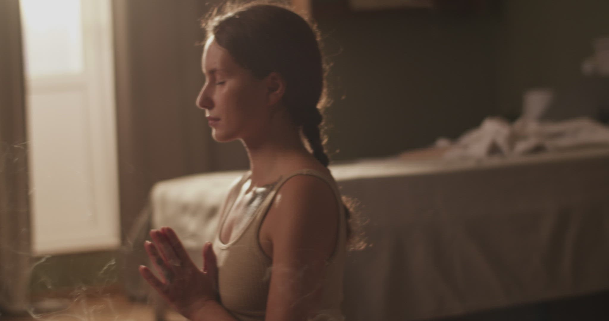 Female meditating near incense in morning