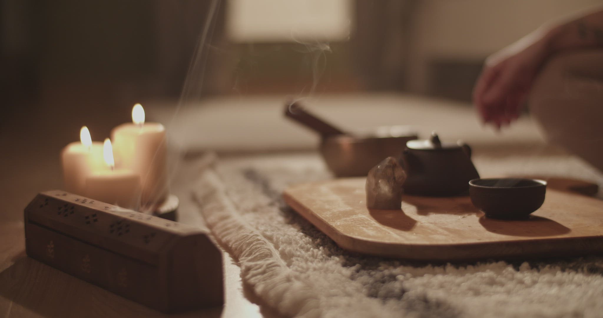 Incense and tea near meditating woman