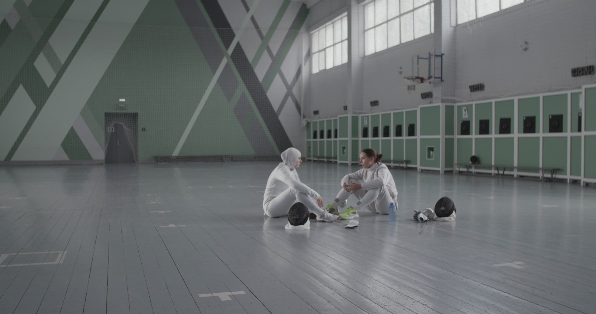 Diverse fencers talking on gym floor