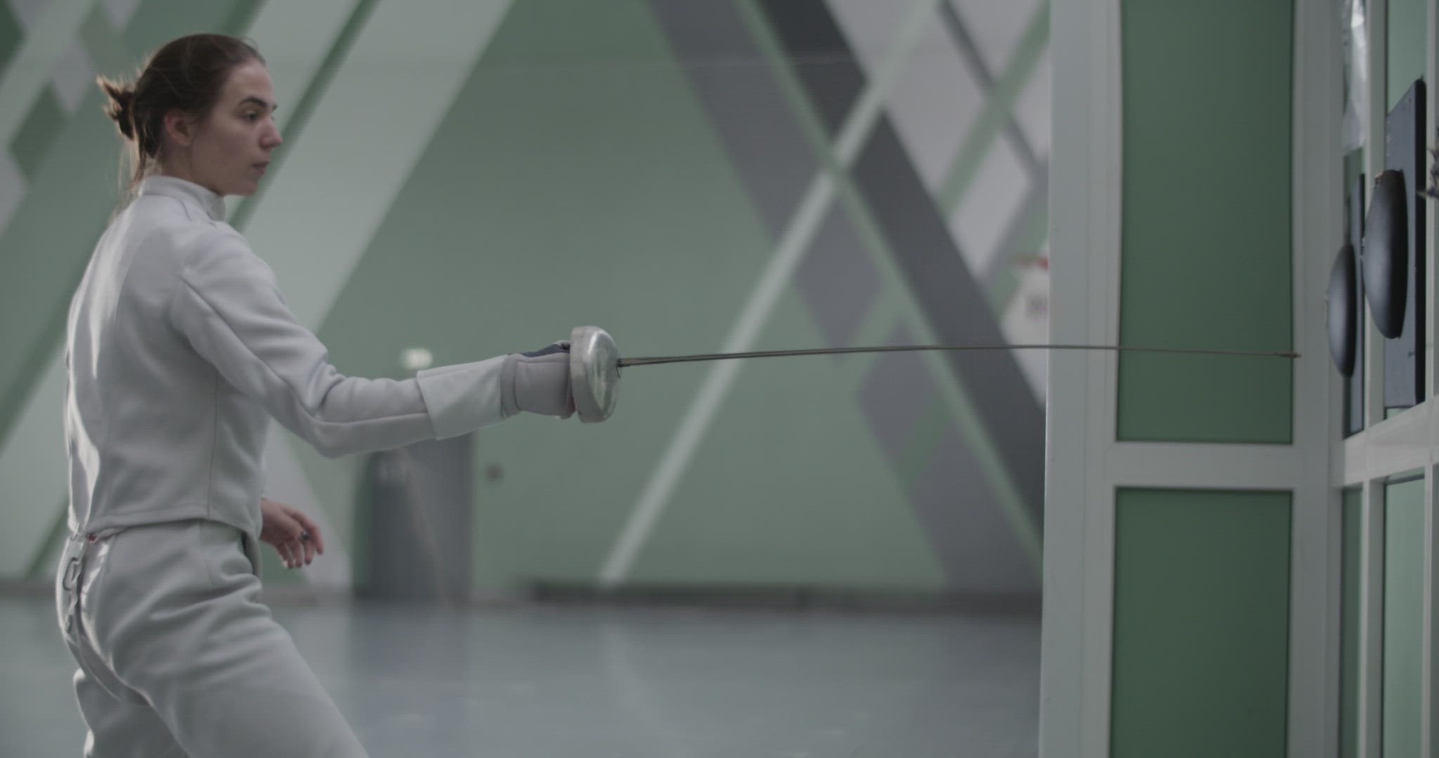 Female fencer practicing strikes in gym