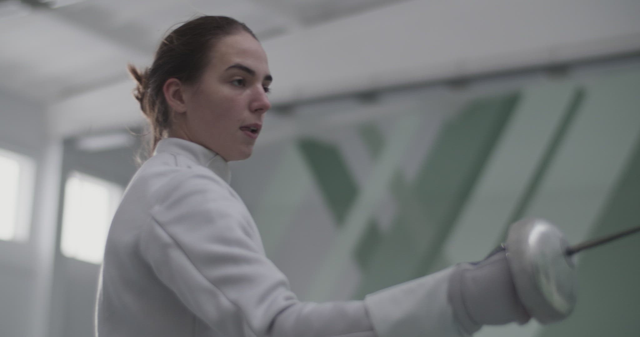 Female fencer practicing strikes in gym