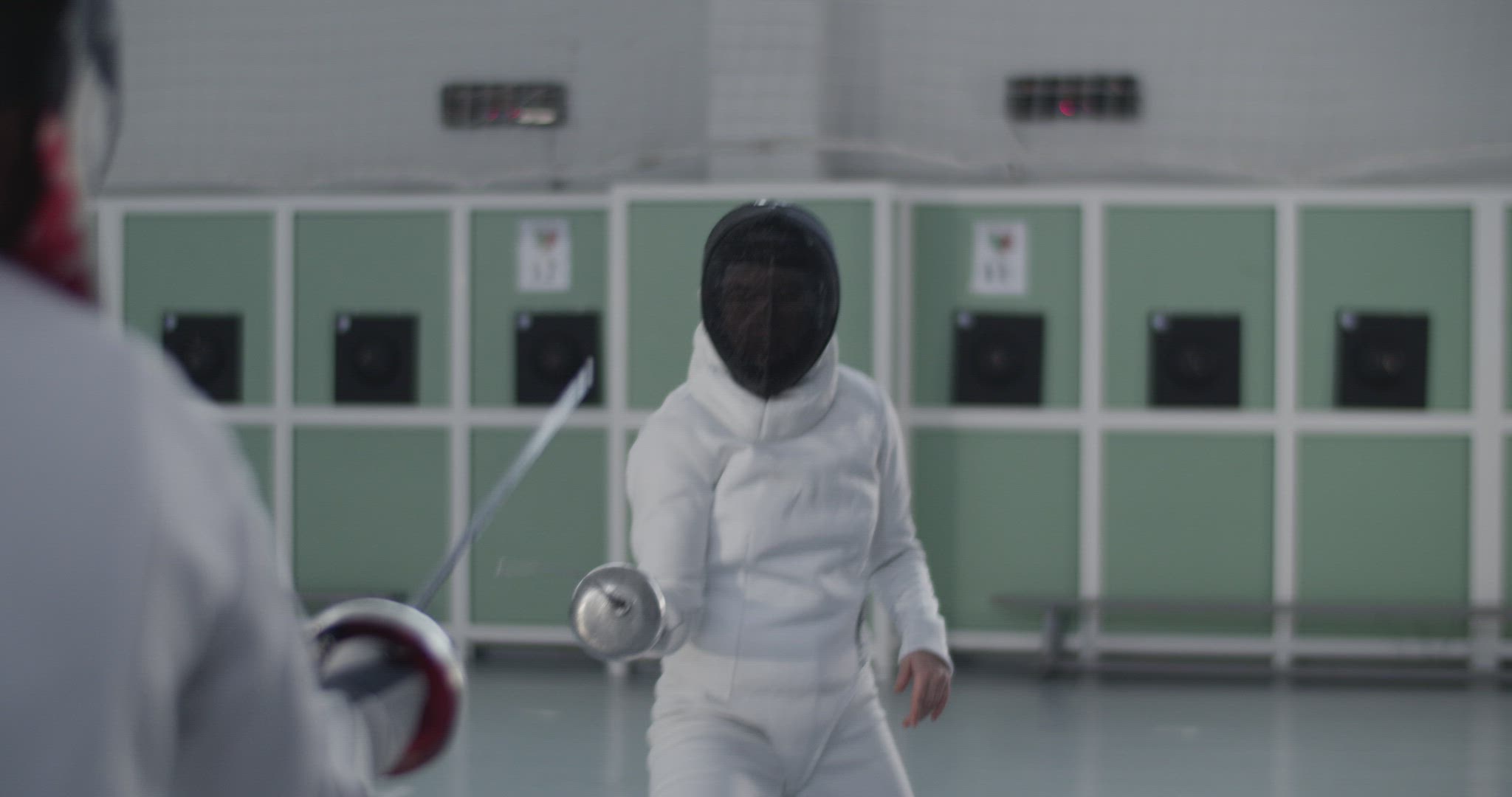 Female fencer attacking opponent with foil