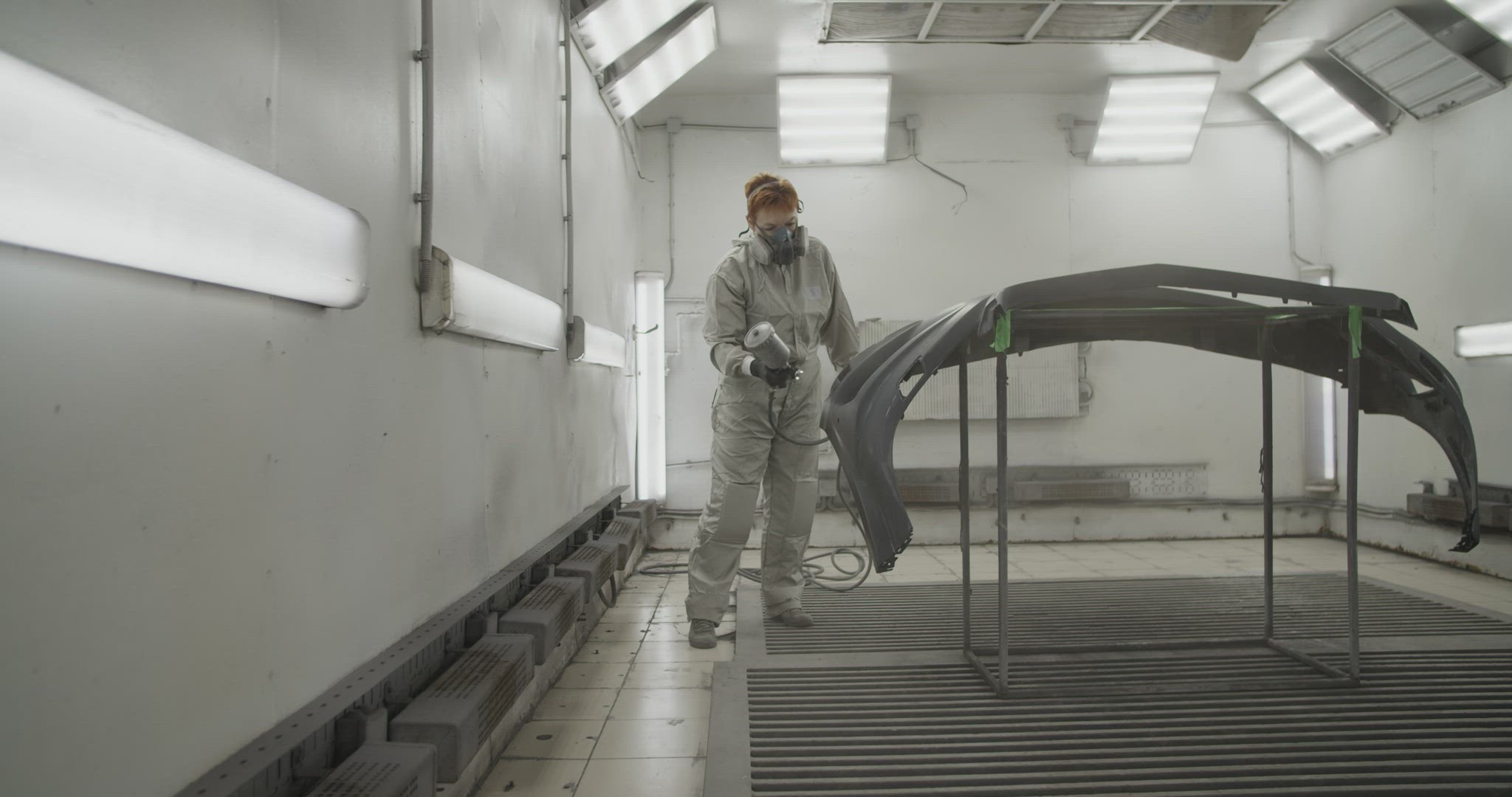 Craftswoman painting car bumper in workshop