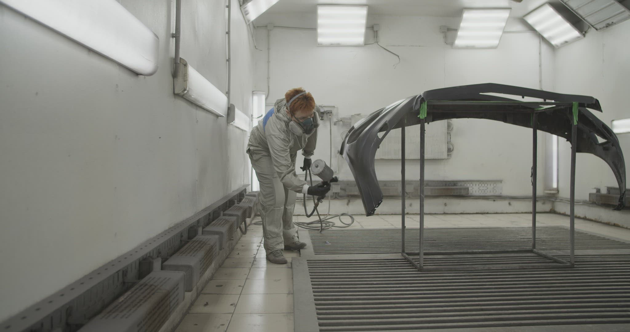 Craftswoman painting car bumper in workshop