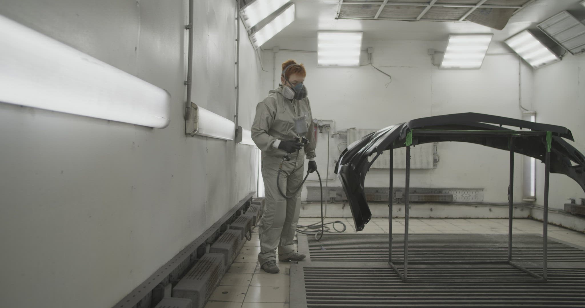 Craftswoman painting car bumper in workshop