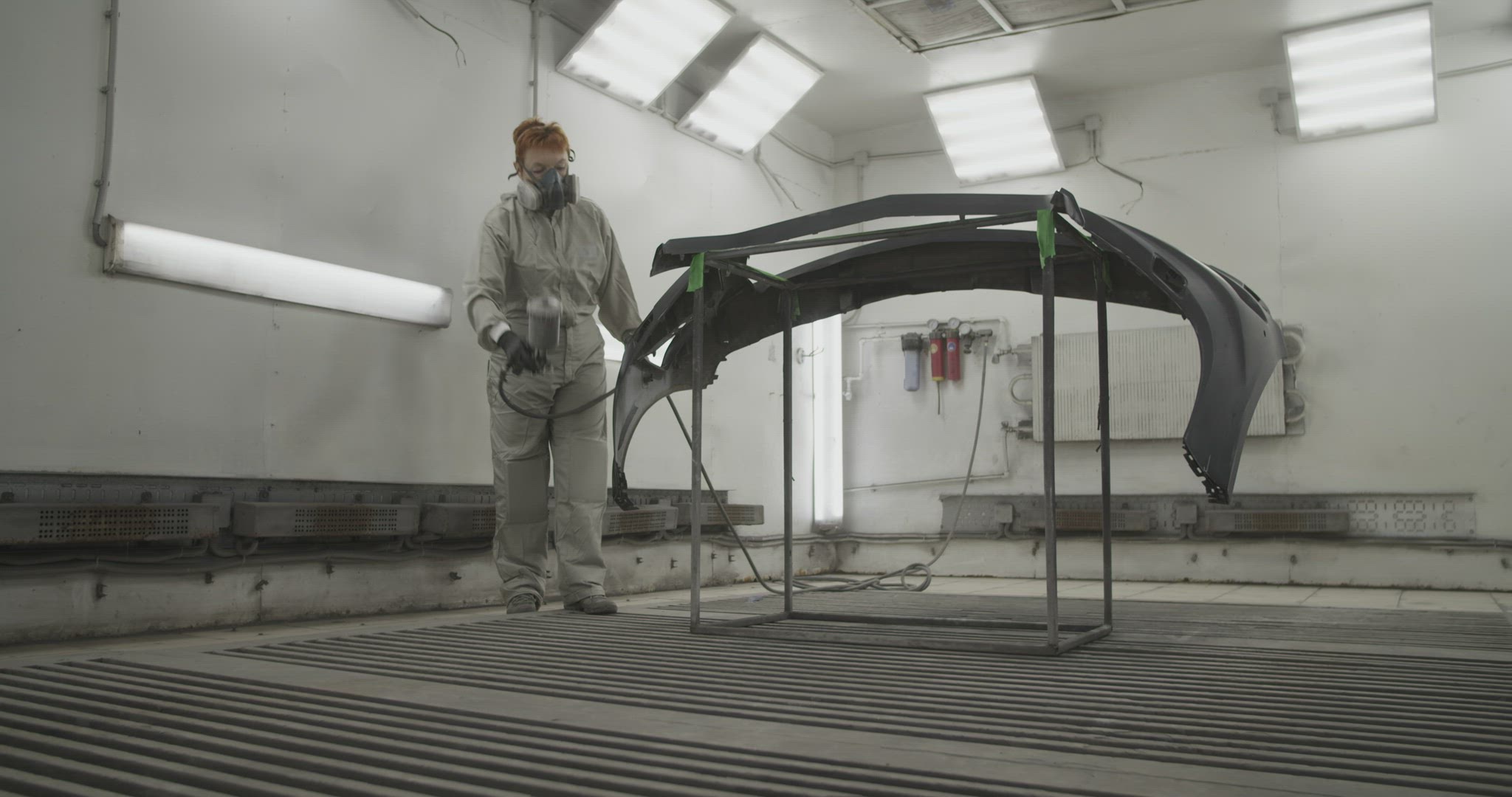 Craftswoman painting car bumper in workshop