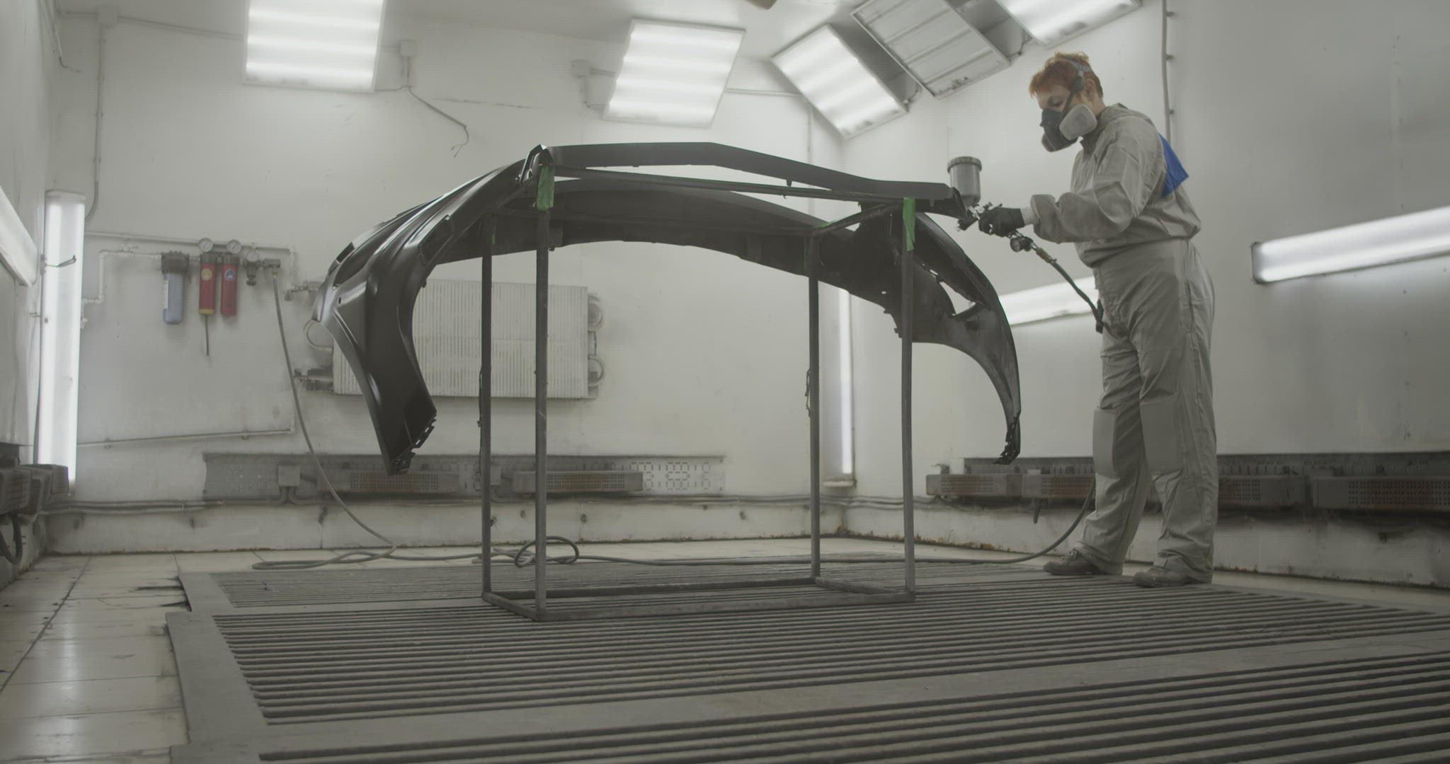 Craftswoman painting car bumper in workshop