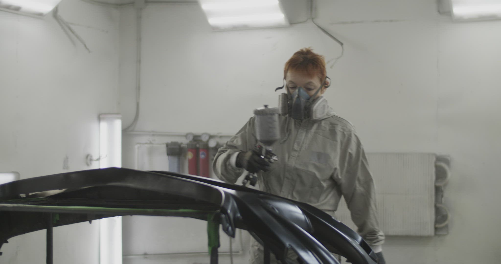Tradeswoman spraying paint over bumper