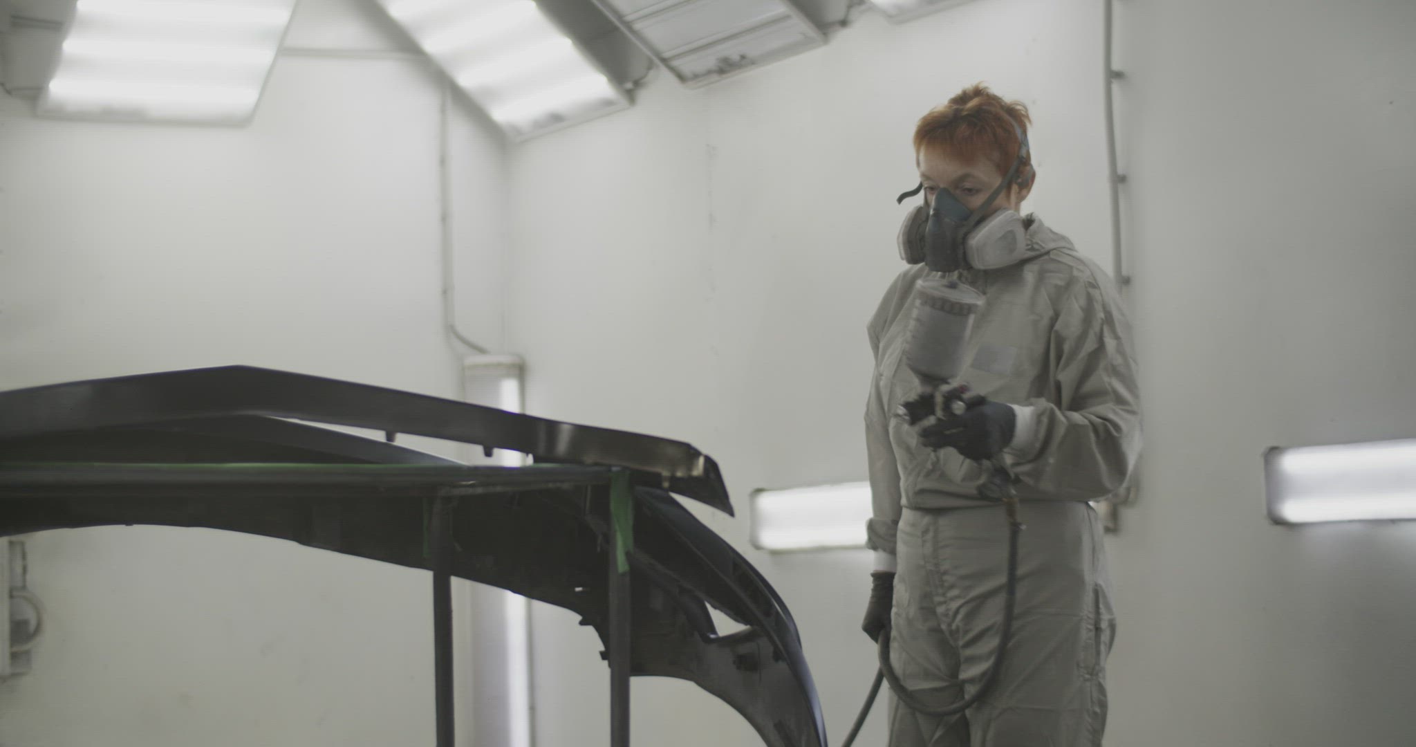Tradeswoman spraying paint over bumper