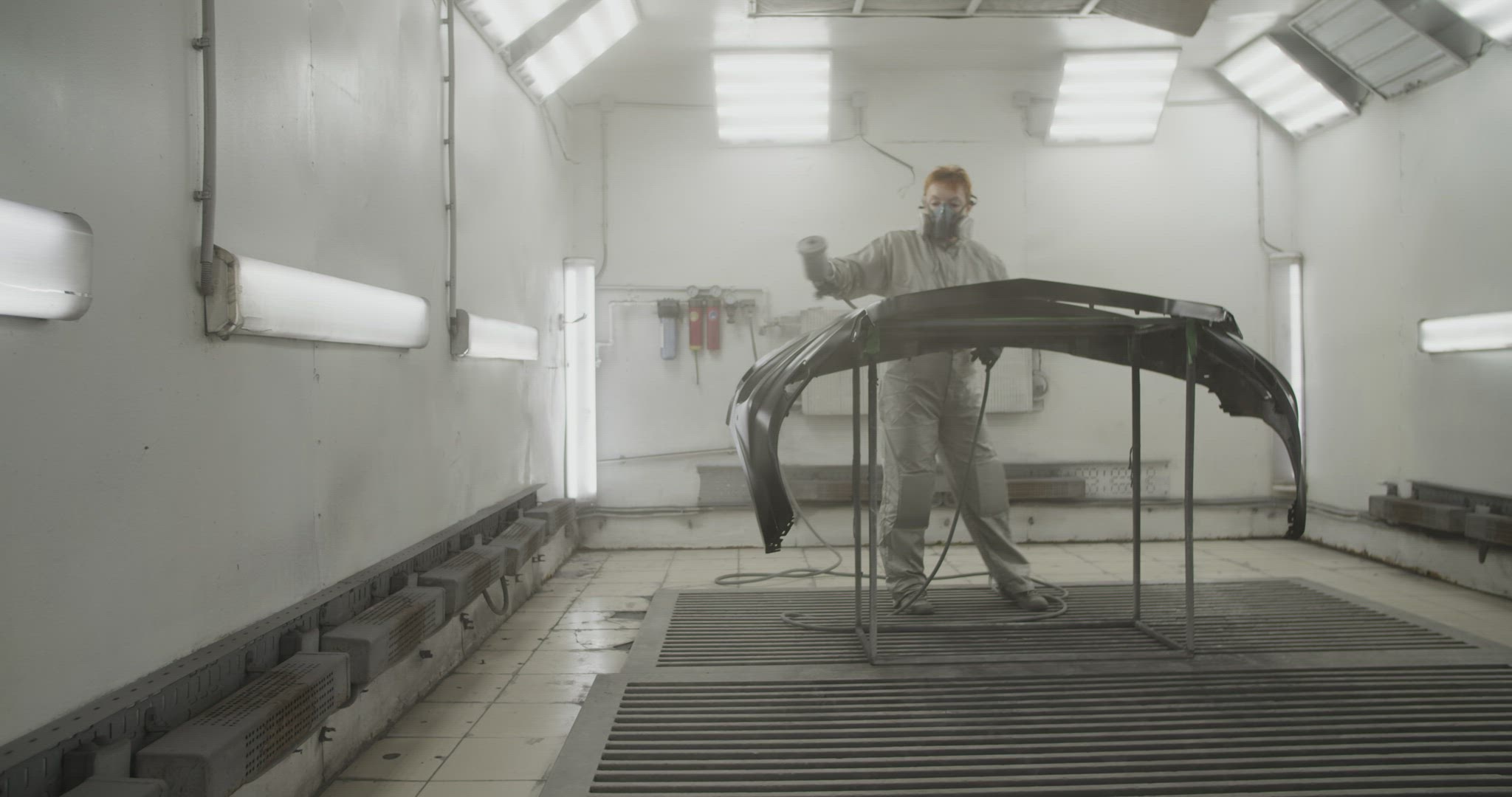 Craftswoman painting car bumper in workshop