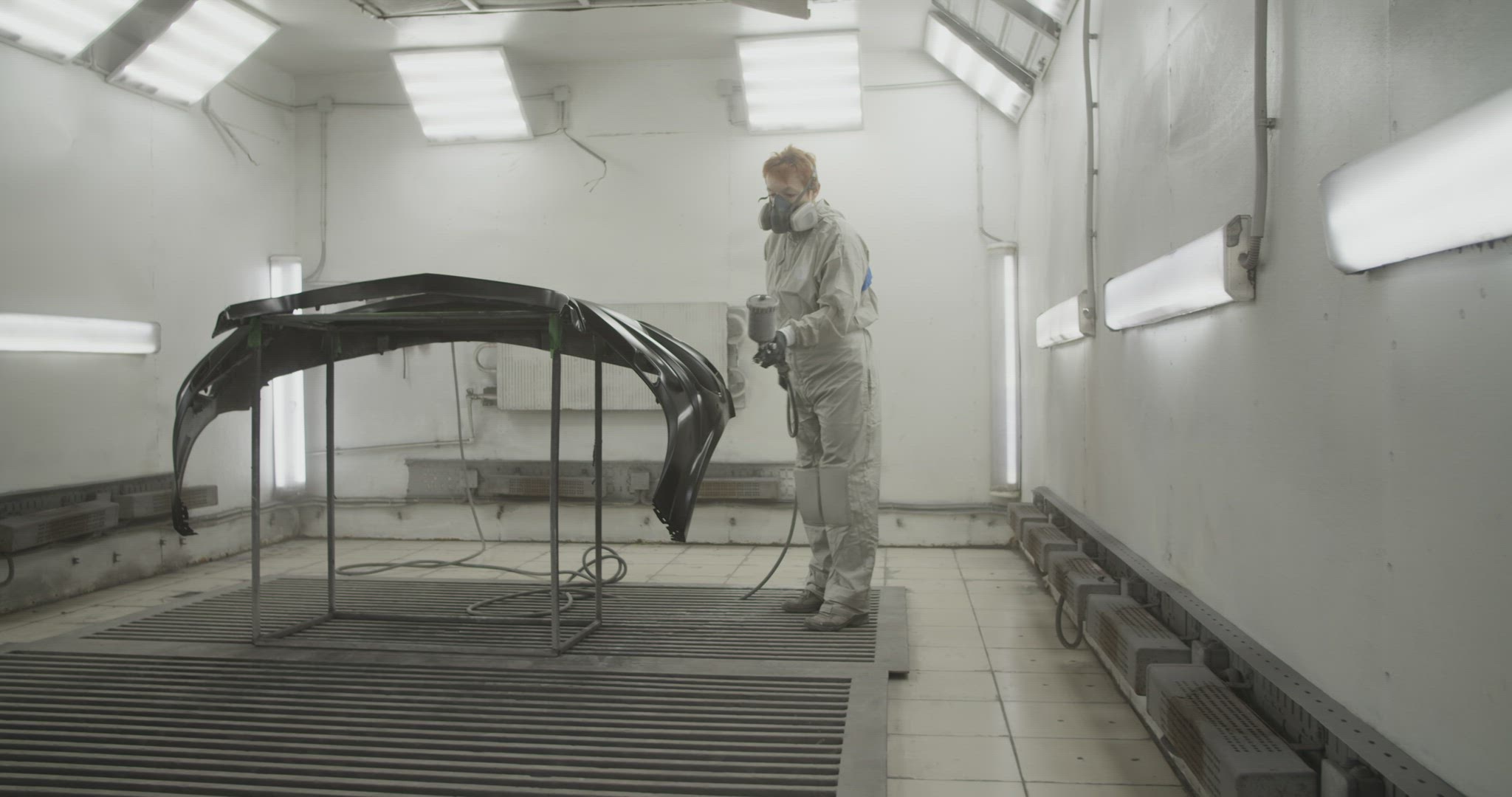 Craftswoman painting car bumper in workshop