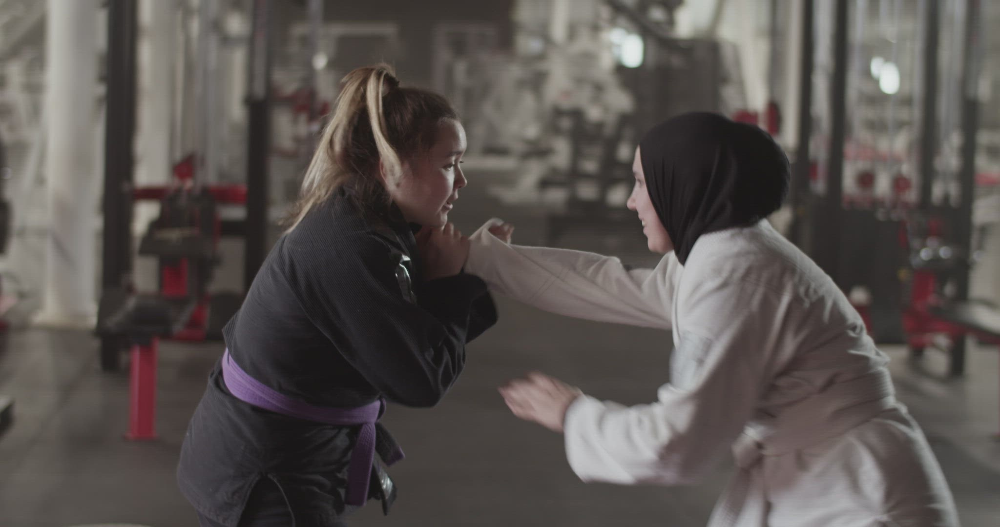 Female wrestlers clinching near exercise machine