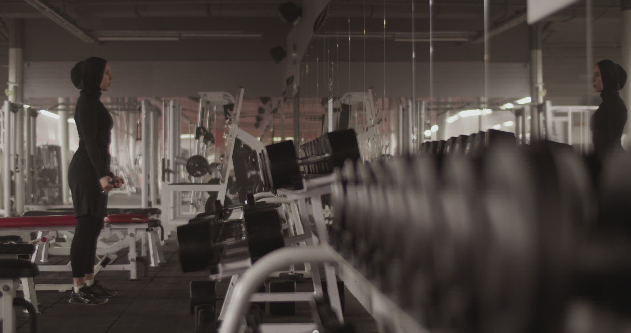 Muslim female athlete doing biceps curls in fitness gym