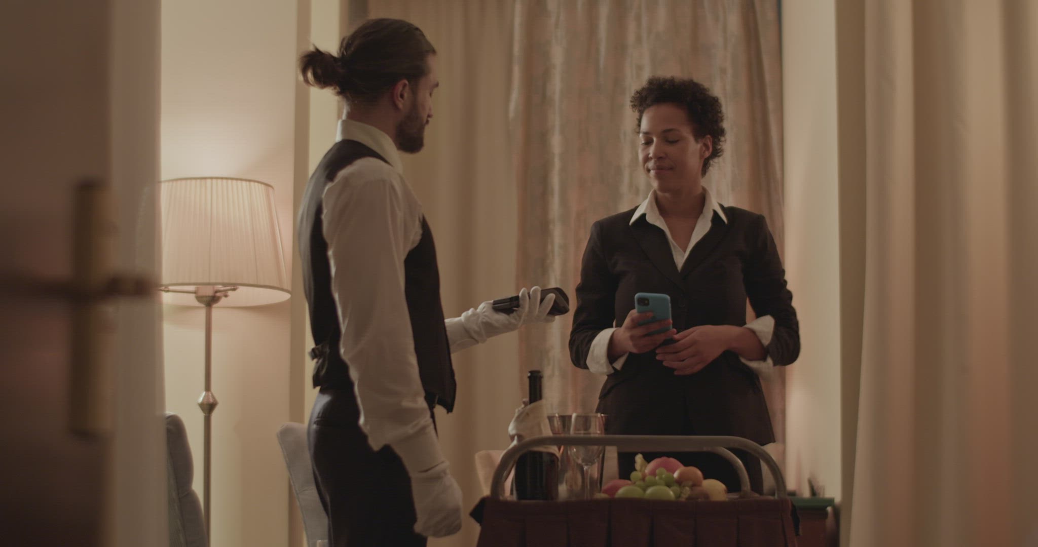 Content ethnic woman paying for order to waiter using smartphone