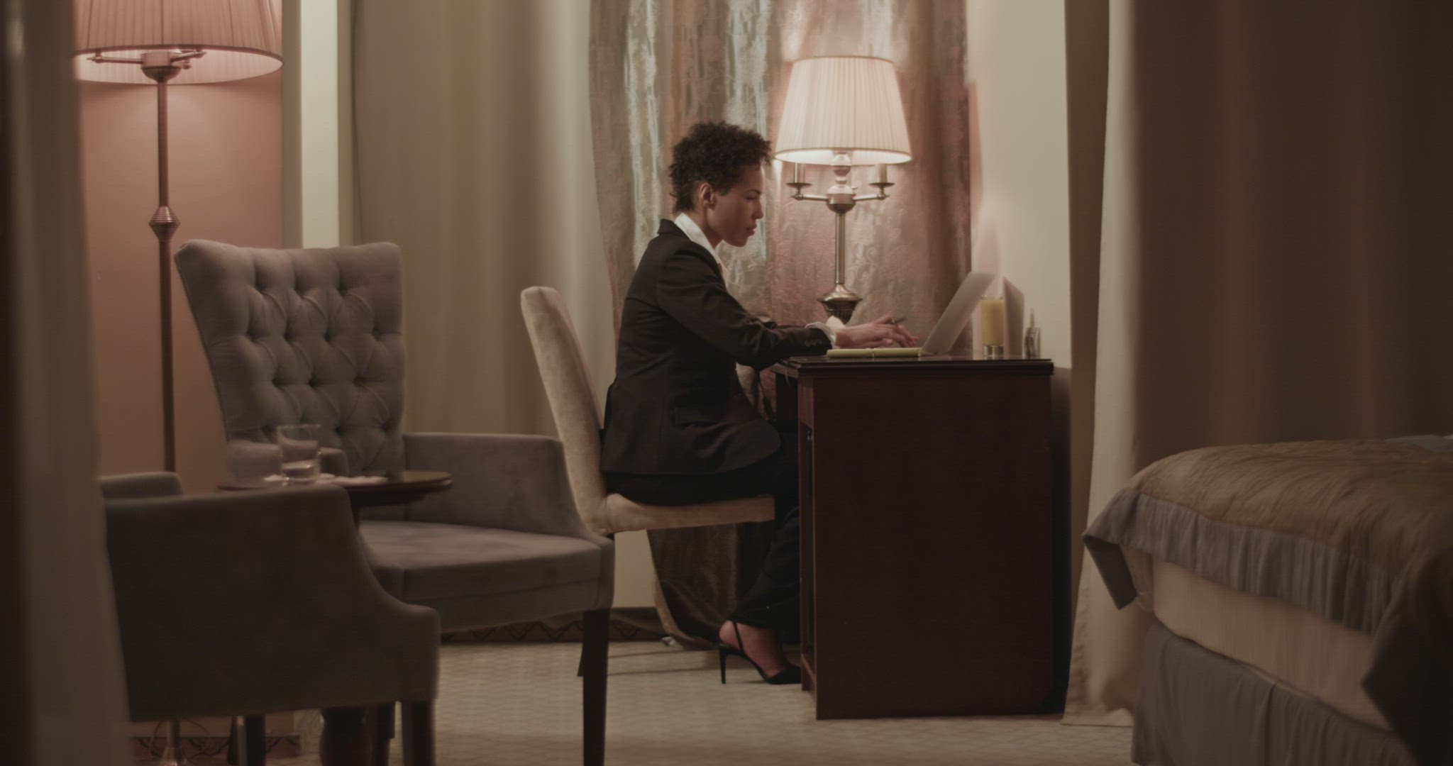 Ethnic woman working remotely on laptop in hotel room during business trip