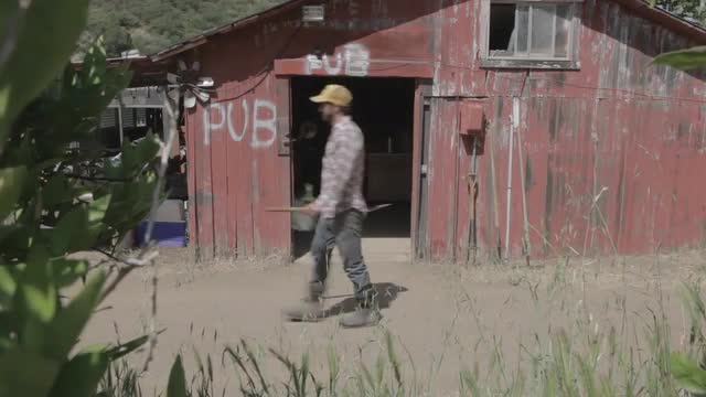 Man farmer on organic farm doing chores near red barn