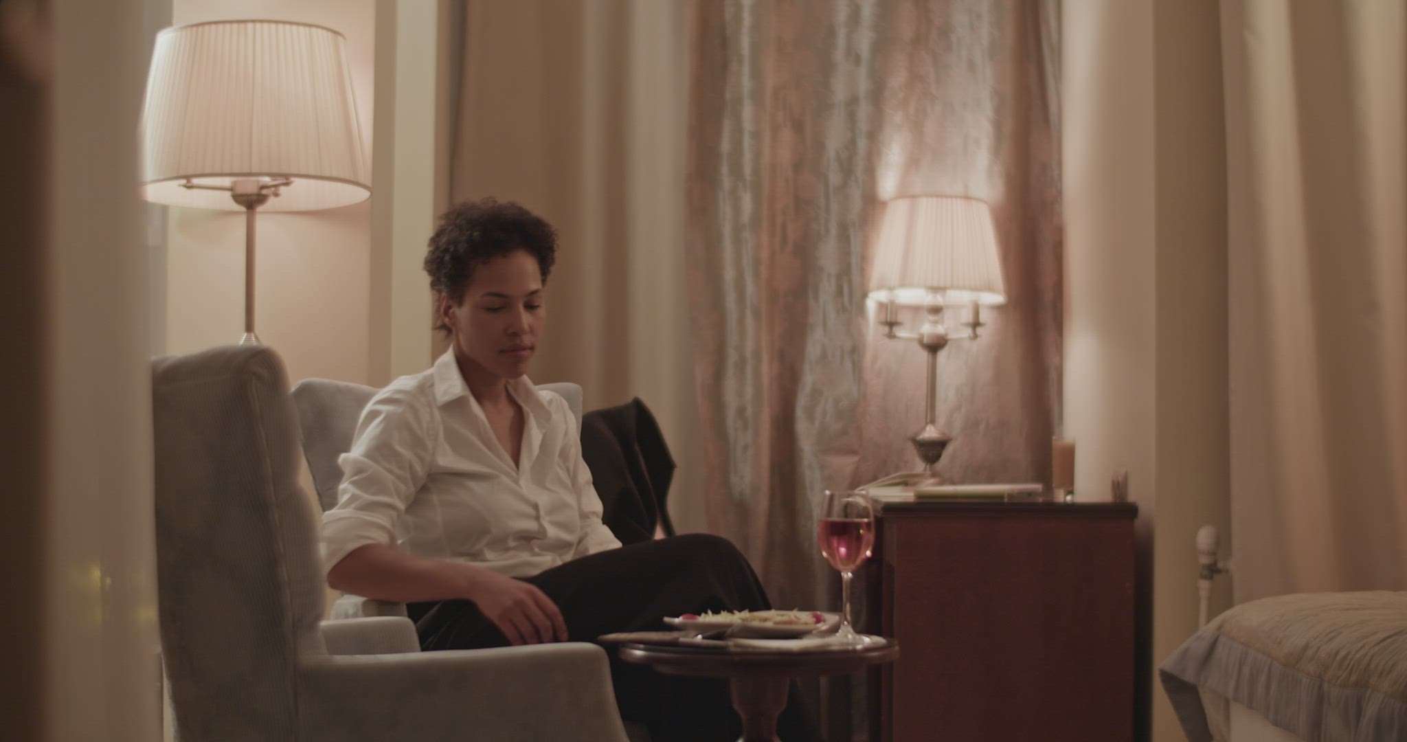 Calm ethnic woman eating in hotel room during business trip
