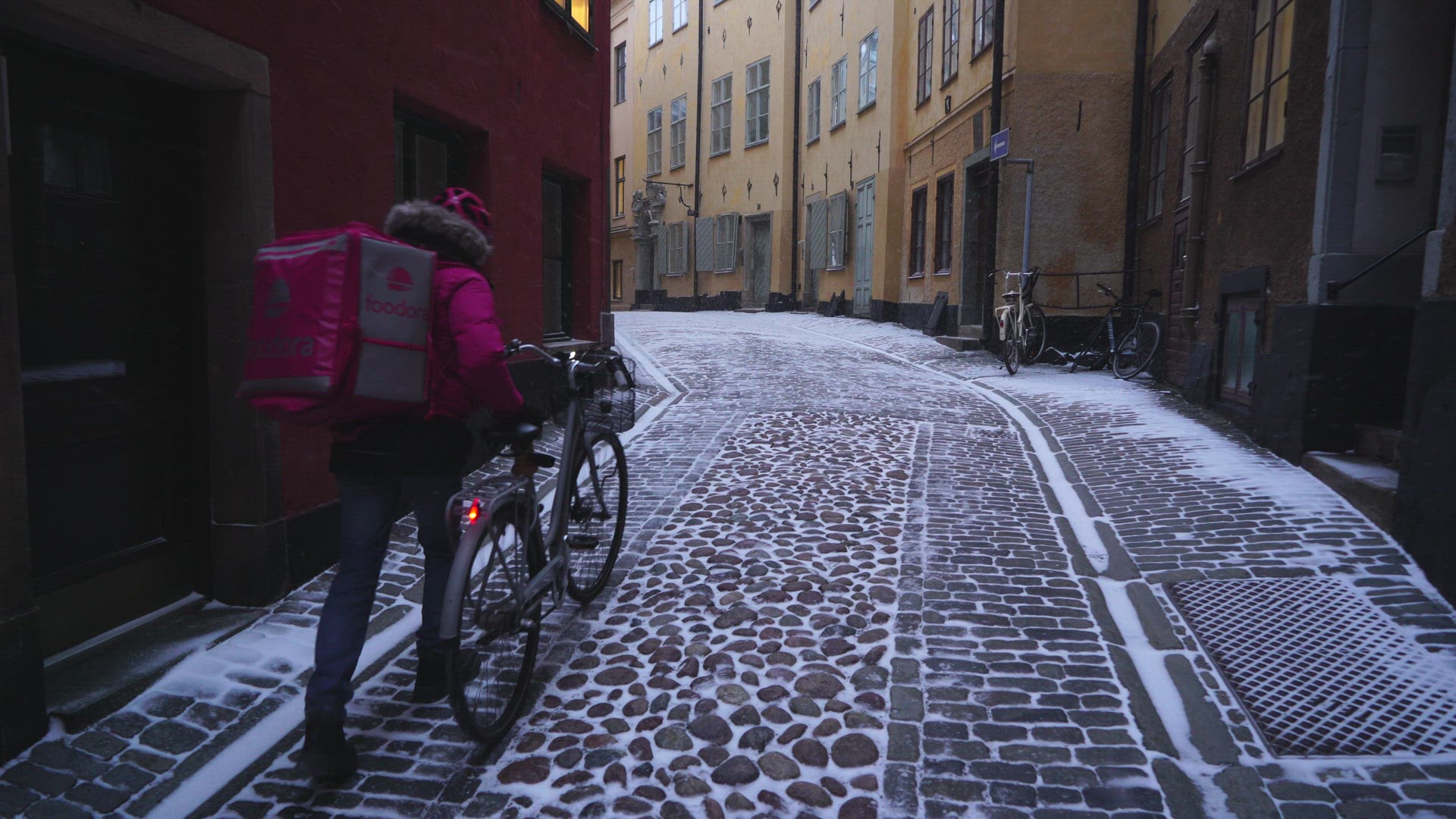 bicycle messenger walking on narrow snowy street in Old Town, Stockholm