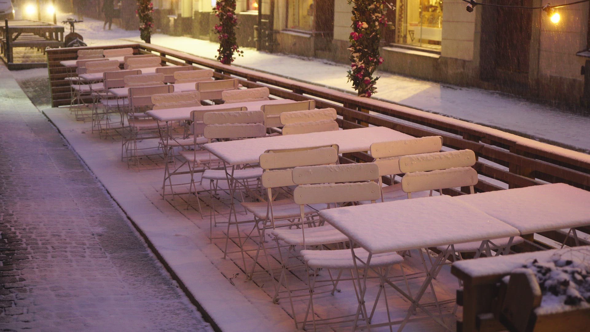 empty outdoor restaurant in old town stockholm - car passing on snow covered narrow street