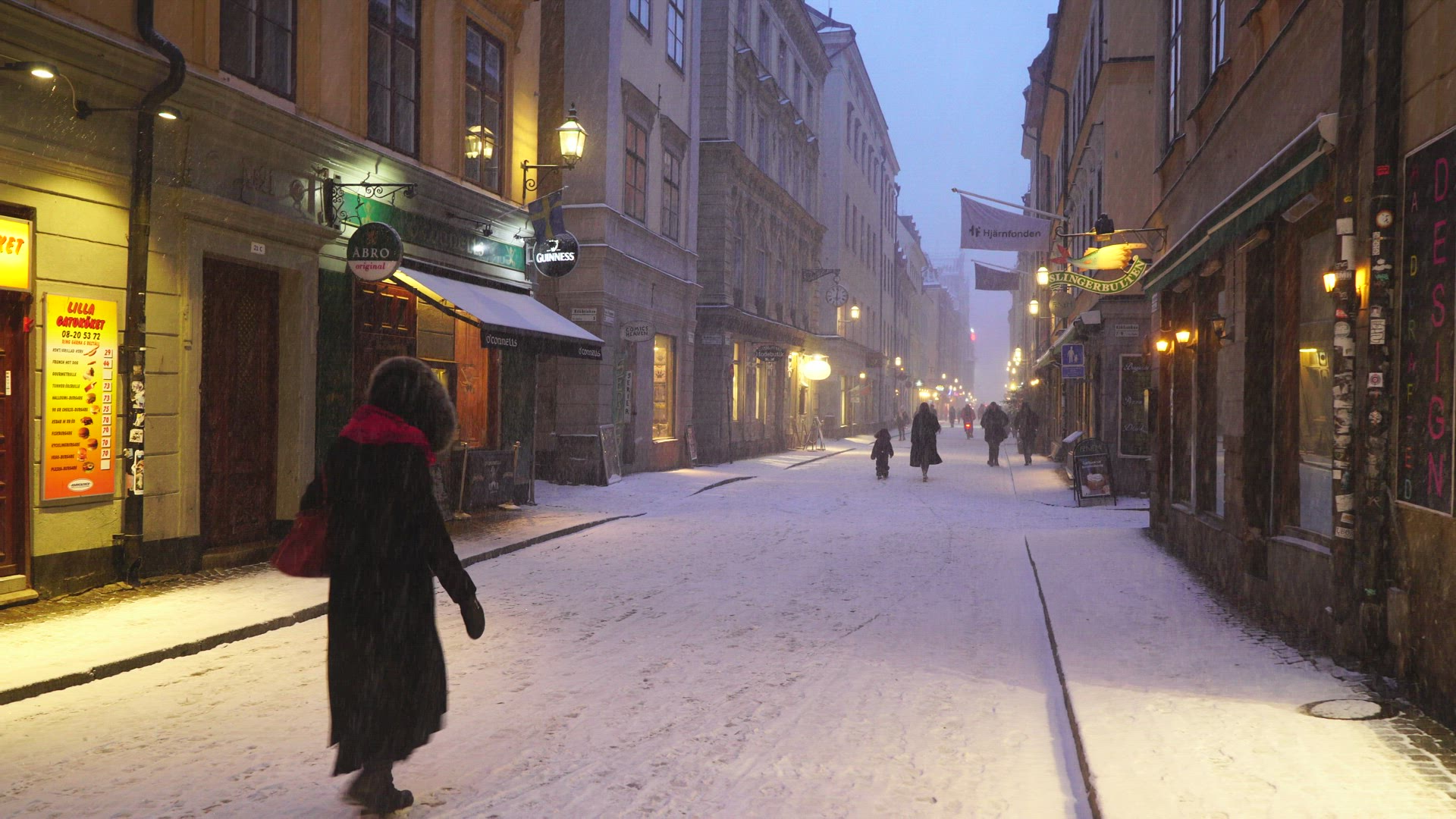 woman crossing narrow street in heavy snowfall - snow falling inold town in Stockholm 