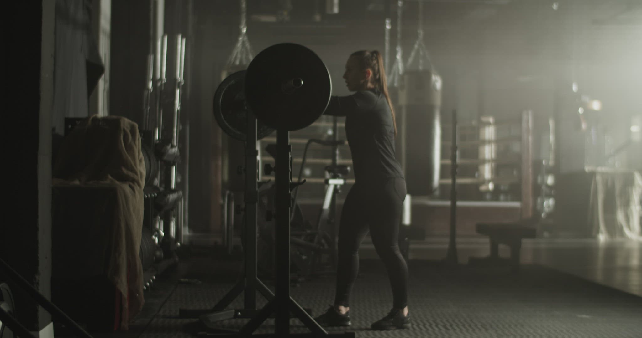 Motivated lady yelling and breathing before workout with heavy barbell