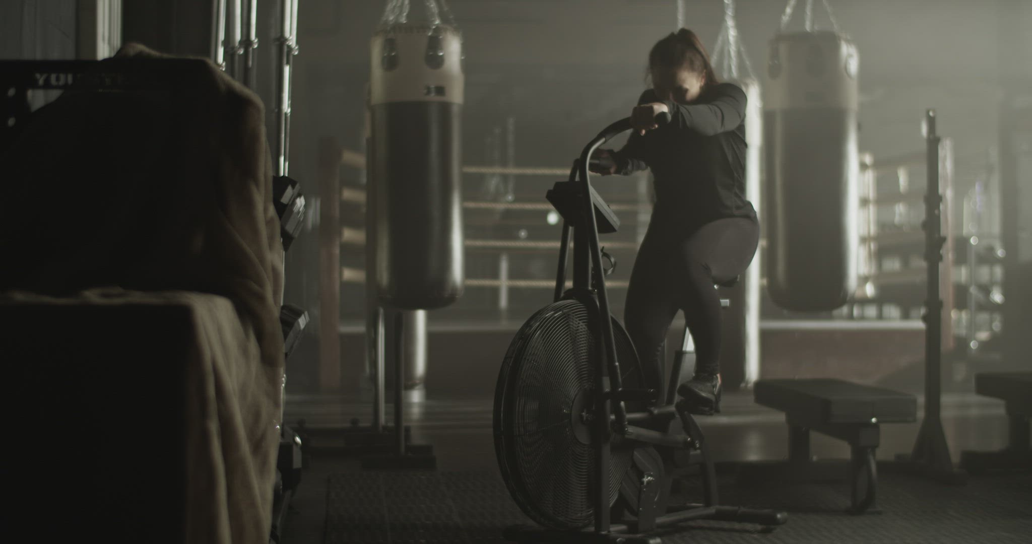 Sporty woman training on air bike in gymnasium