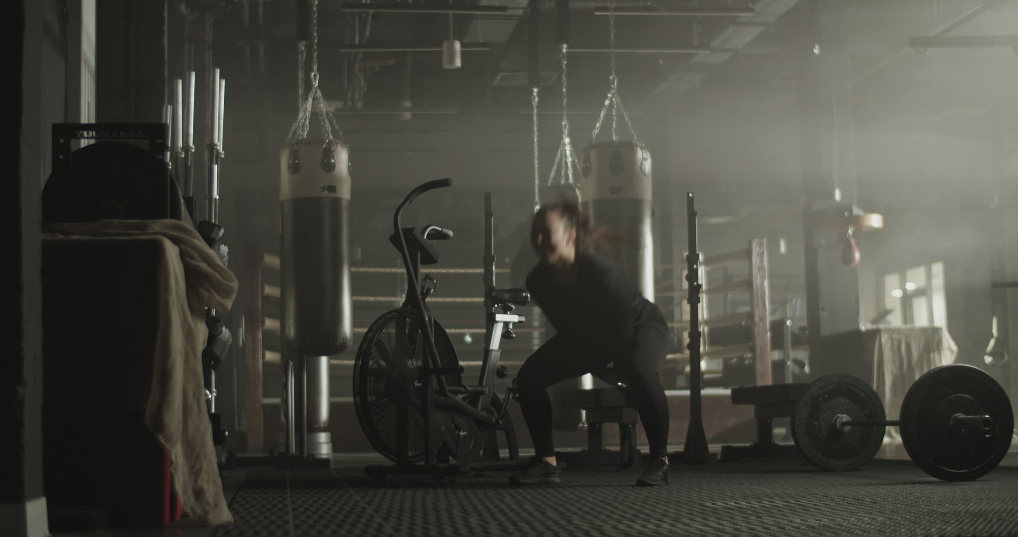 Athletic woman squatting and swinging kettlebell in gym